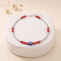 Close-up of red beads and a blue evil-eye charm on the Silvme 925 sterling silver red bead evil eye anklet