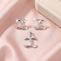 Interlocking crescent pendant and matching studs styled on soft pink satin