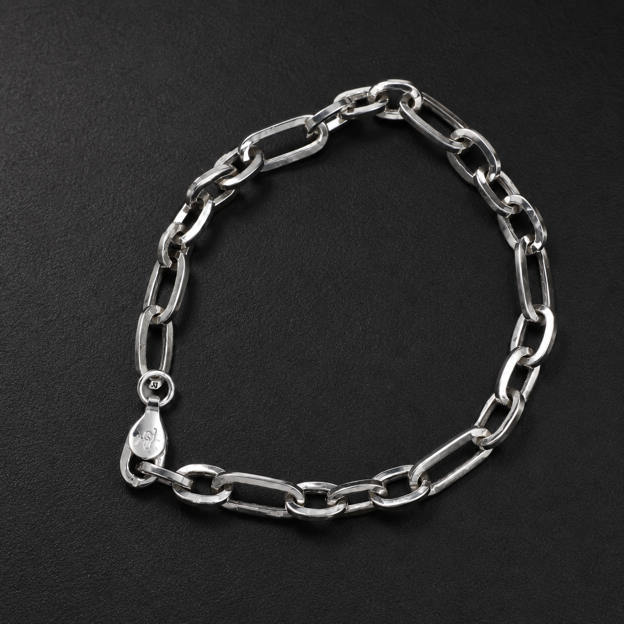 Full length of the elongated figaro bracelet showing its polished silver-tone finish