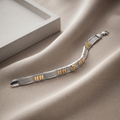 Close-up of ribbed rectangular bars broken up by gold-tone accent panels and a central emblem on the Silvme two-tone bar link