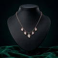 Rose gold leaf pendant necklace with pavÃ©-set clear stones, displayed on an open vintage book.