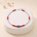 Close-up of red beads and a blue evil-eye charm on the Silvme 925 sterling silver red bead evil eye anklet
