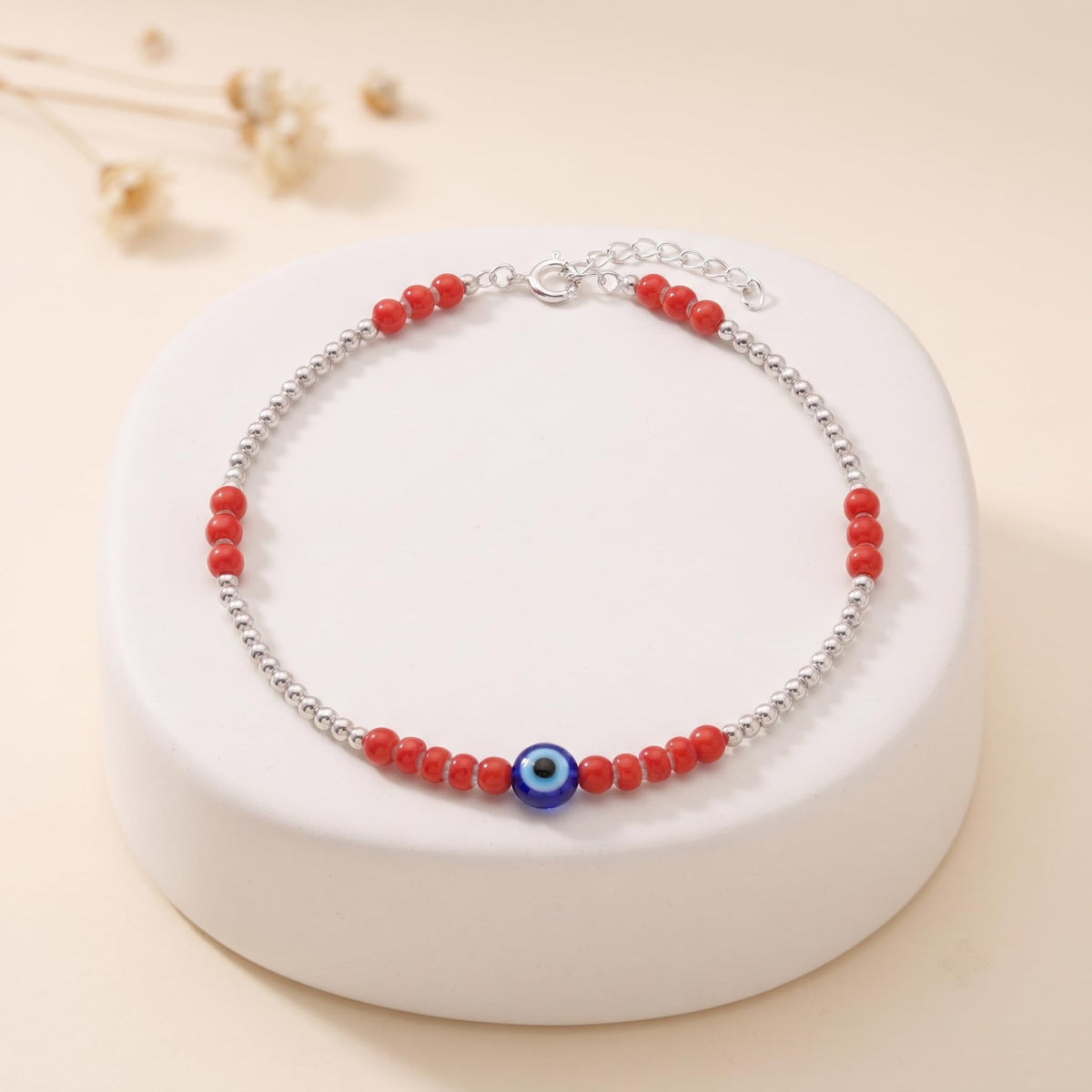 Close-up of red beads and a blue evil-eye charm on the Silvme 925 sterling silver red bead evil eye anklet