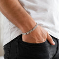 Full length of the solid flat curb chain bracelet showing its polished silver-tone finish