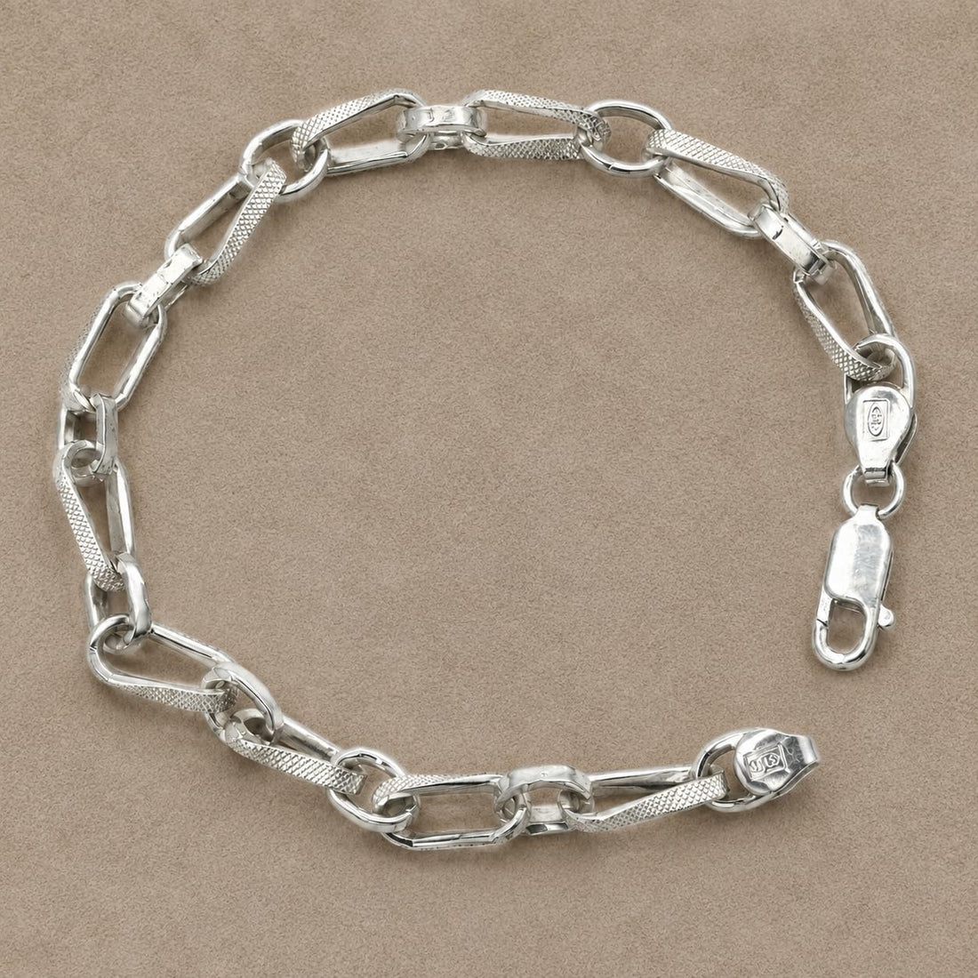 Close-up of elongated paperclip links with a brushed, cross-hatched surface between round connectors on the Silvme textured p