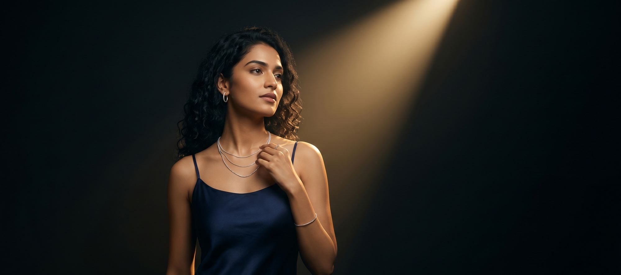 Woman in a dark blue dress standing under a spotlight on a black background